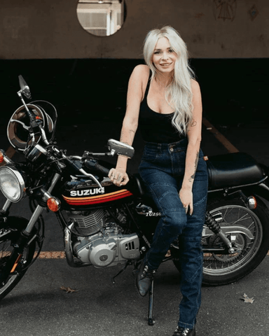 An image of a blonde woman leaning on her motorcycle wearing the Ellie motorcycle jeans (womens fit)