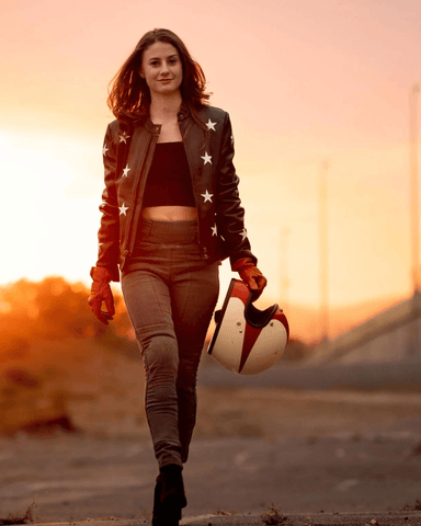 An image of a brunette woman walking towards the camera holiding a helmet wearing the Melissa skinny motorcycle jeans for women