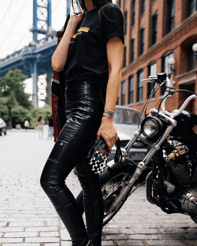 An image of a woman standing in front of her bike wearing the faux leather Lane leggings