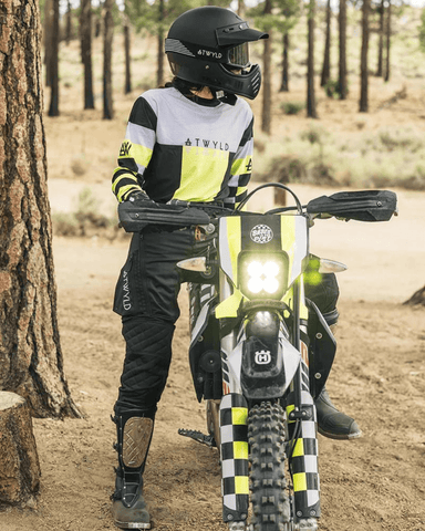 An outdoor image of a woman sitting on her dirt bike wearing the Velocity Off-Road motorcycle pants for women