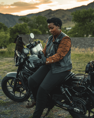An image of a black woman sitting on her bike at sunset wearing the Moto Ribbed Pants for motorcycle riding