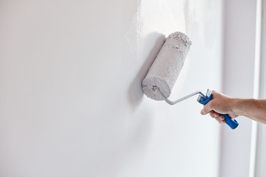 someone applying white paint with a paint roller