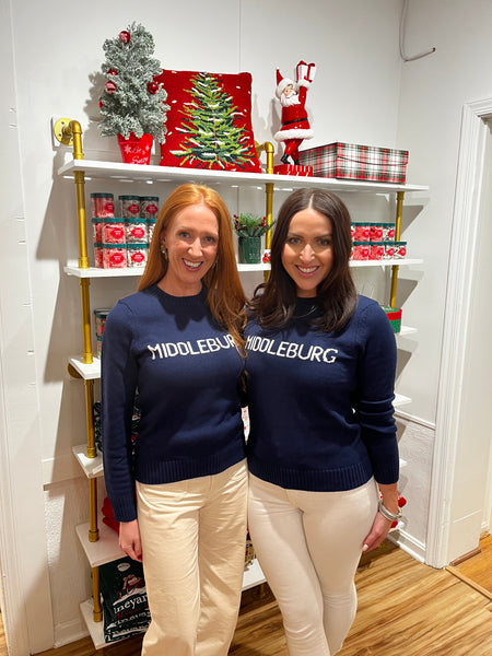 Two women wearing Middleburg embroidered sweaters in front of holiday decor