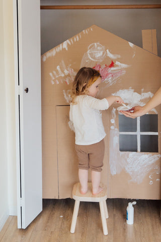 Girl painting a cut-out of a house to symbolise home building