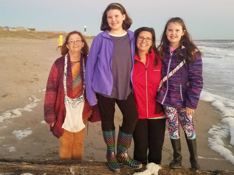 grandmother, daughter and grand daughters combing the sea shore for shells.