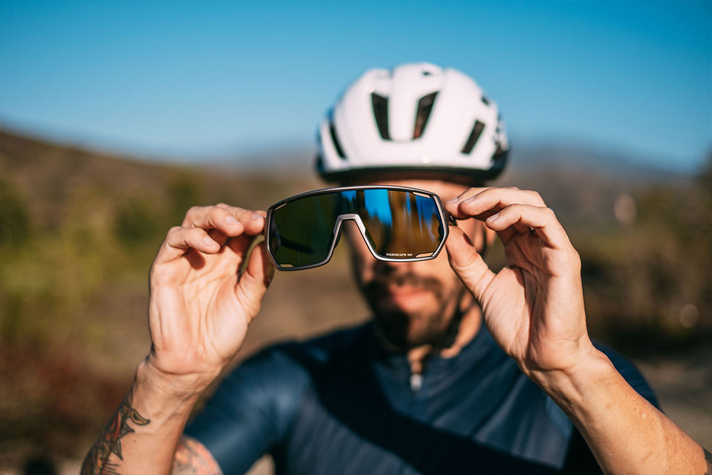 male gravel bike rider holding a pair of Shimano's new Technium Ridescape sunglasses