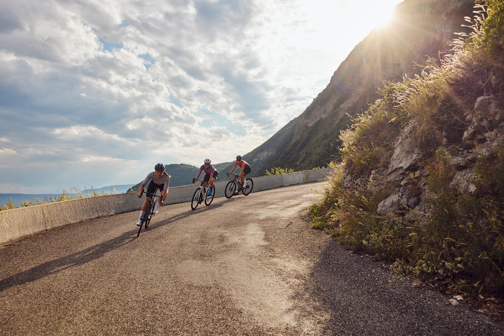 Women riding a road bike down a mountain road at sunset with Shimano shoes