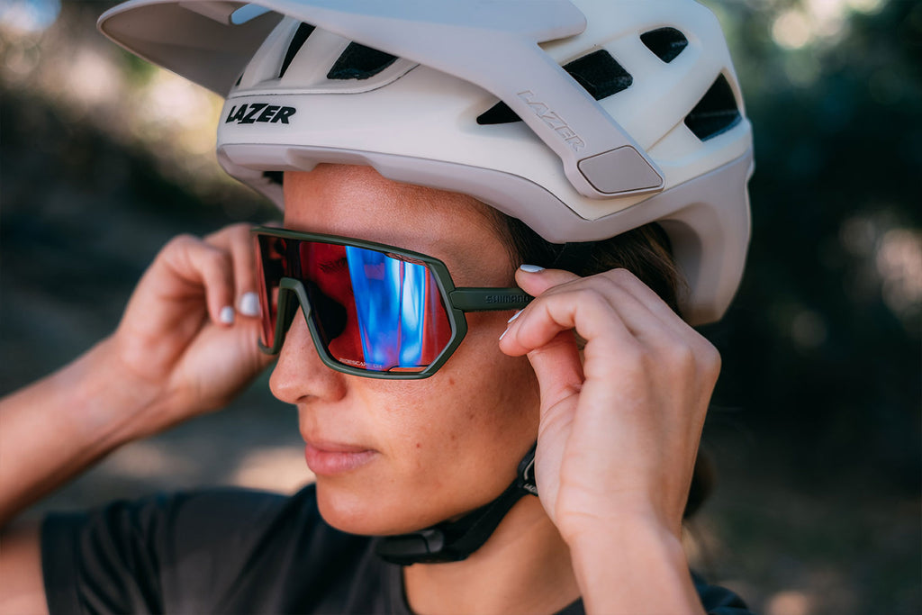 Women putting a pair of Shimano Ridescape MTB sunglasses