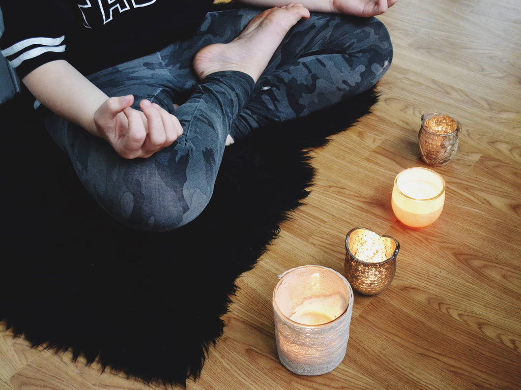 Frau meditiert vor Kerzen