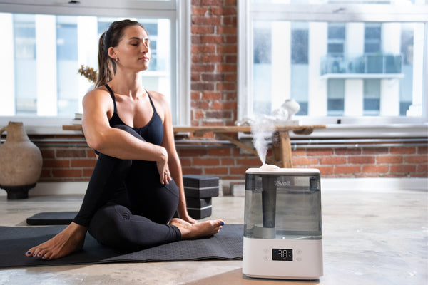 Woman on yoga mat next to Levoit Classic 300S humidifier