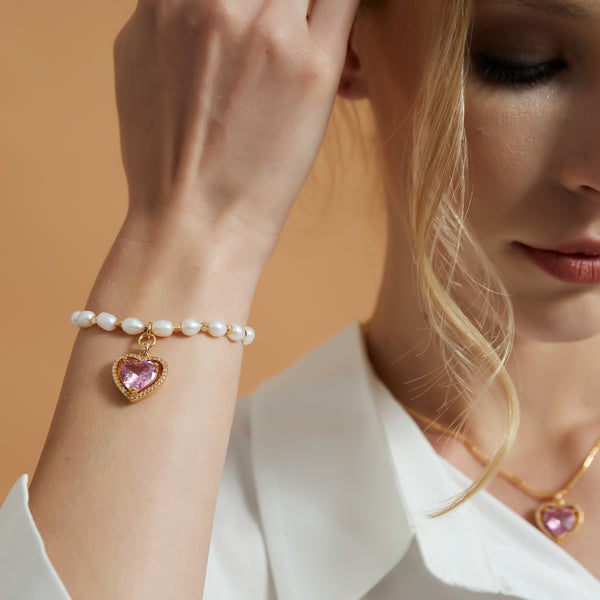 Elevate your style with our Pink Crystal Heart Natural Pearl Bracelet, a harmonious blend of elegance and charm. This exquisite piece features high-quality pink crystals meticulously cut to radiate brilliance, complemented by the timeless allure of natural pearls. The focal point is a dazzling crystal heart that adds a touch of romance and sophistication to any outfit.