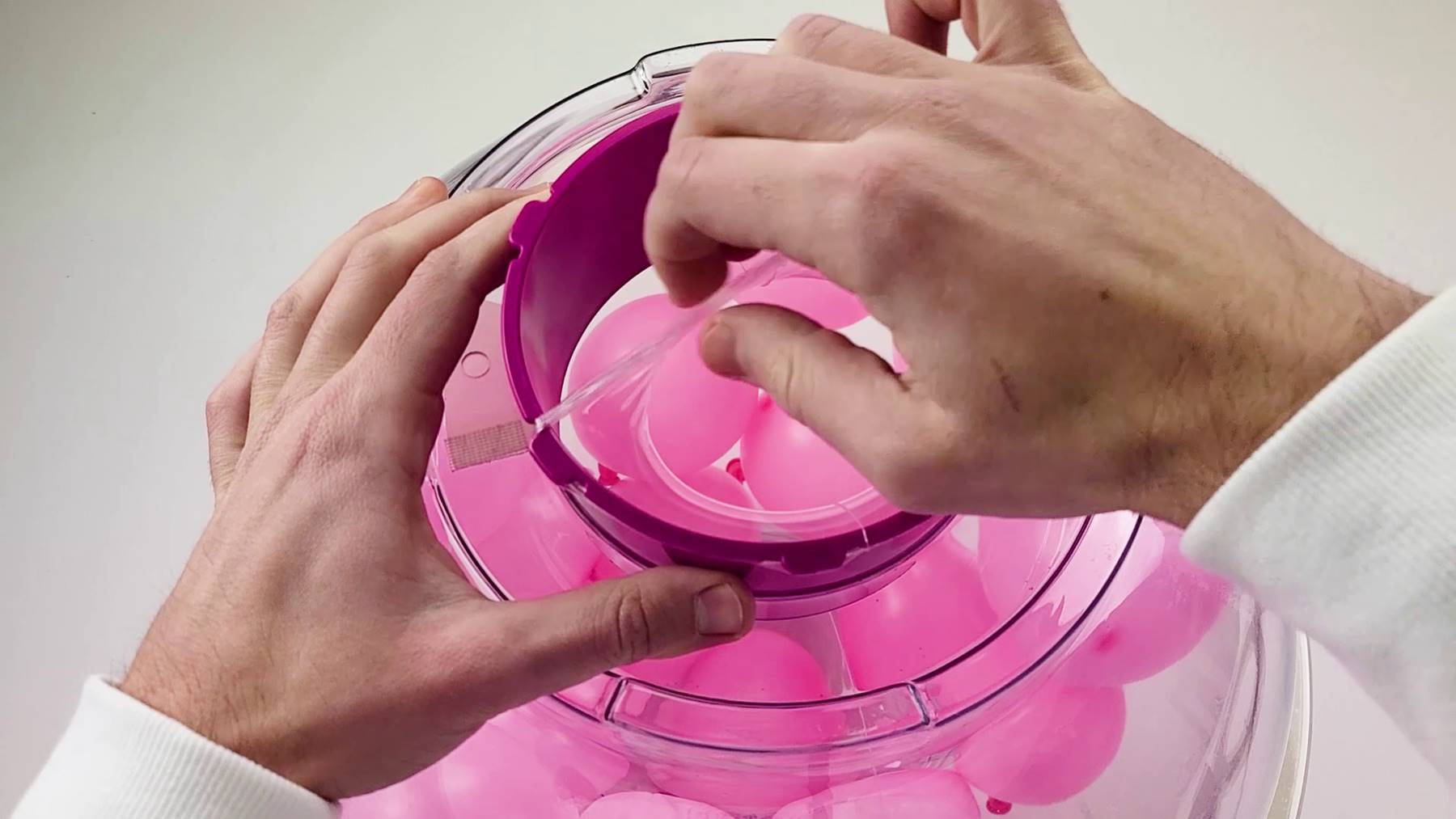 A hand detaching the balloon neck from the knobs on the balloon stuffing machine