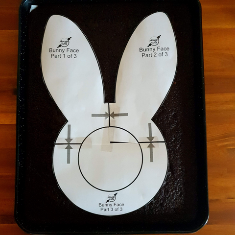 Image of Easter Bunny Face baking stencil on cake ready to be cut around.