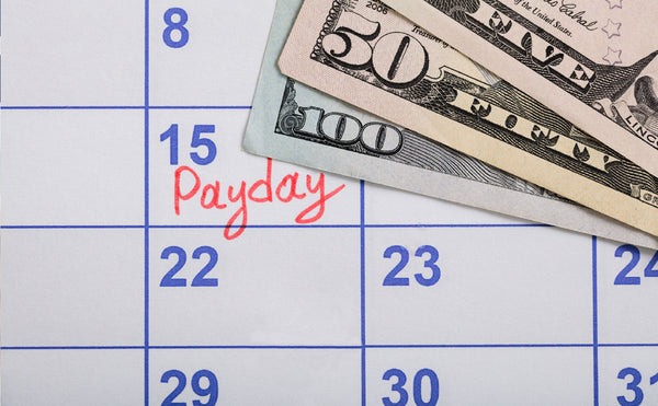 Money laid over a calendar with "Payday" written on the 15th.