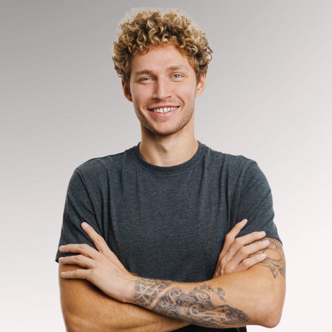 Gentleman in a gray tee shirt smiling demonstrating a curly hair type for men