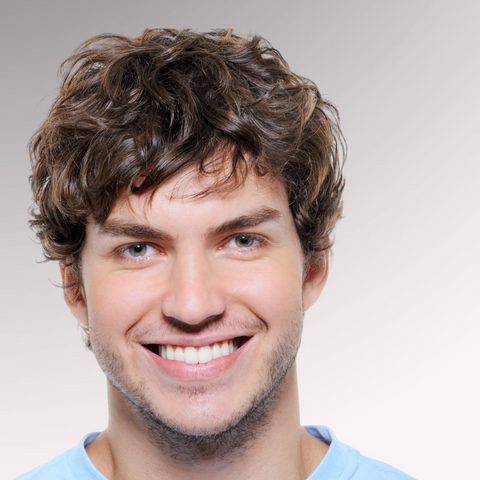 Man in a blue shirt with a big smile demonstrating a medium-length tousled hairstyle