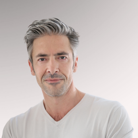Gray haired man with medium length hair demonstrating a low maintenance classic comb over hairstyle for men