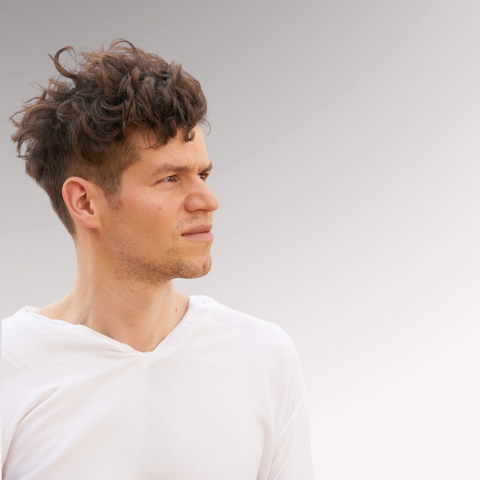 Man in a white shirt looking to the distance with medium-length hair demonstrating a textured waves hairstyle for men