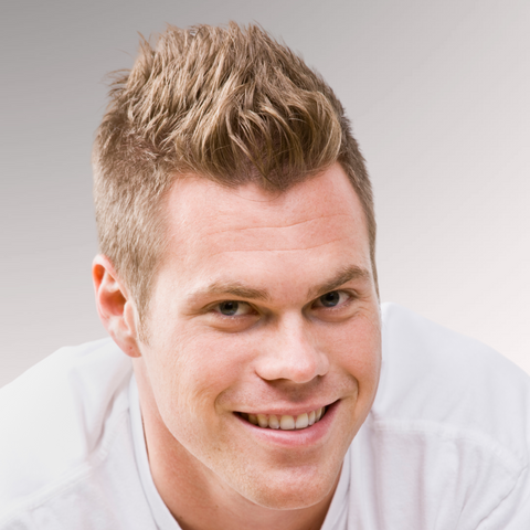 Man in a white shirt with sand blonde hair smiling demonstrating a faux hawk hairstyle for men who have fine, thinning hair