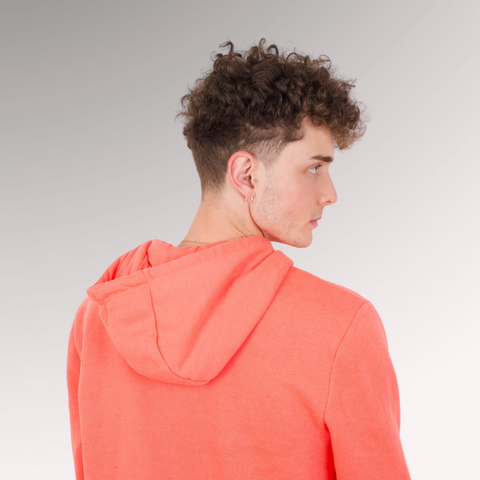 Man in a peach sweatshirt with curly hair demonstrating a curly fade hairstyle for men who have curly, thin hair