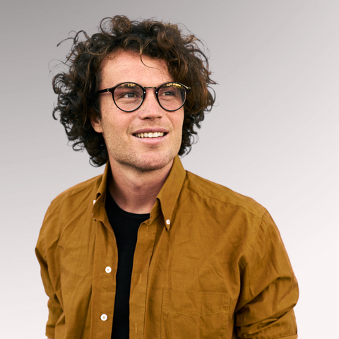 Man in a brown button up shirt with glasses who has curly hair demonstrating a curly mop hairstyle for men who have thin, curly hair