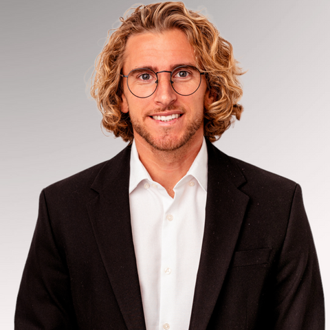 Man with wavy hair and glasses in a suit demonstrating a styled beachy waves professional men's haircut