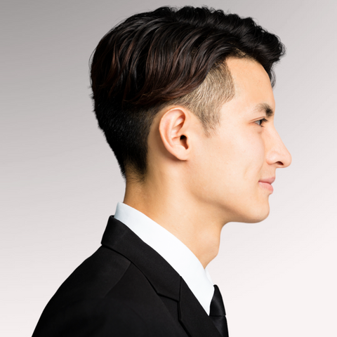 Man in a suit with black hair demonstrating an undercut professional men's haircuts