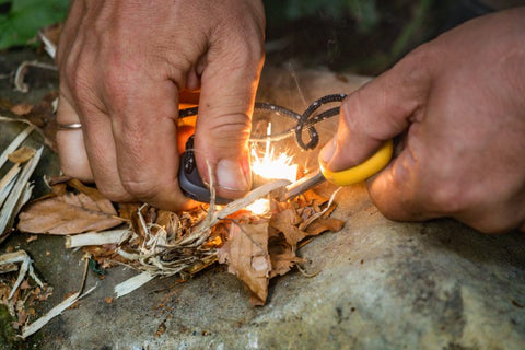 A hand igniting a fire using a fire starting tools