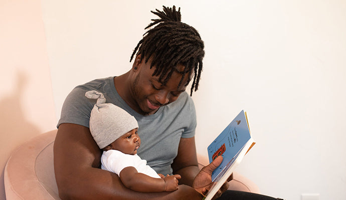 Dad reads colorful baby book to chubby, adorable young son.