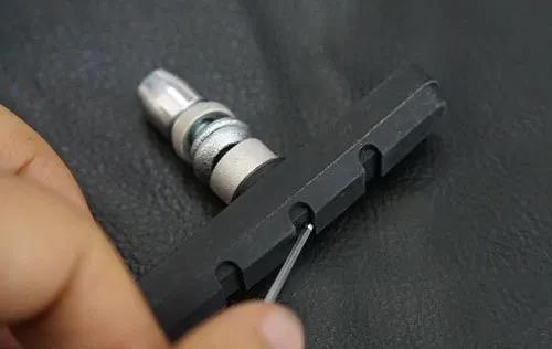 Use a small stick to clean the crevices of the brake pad