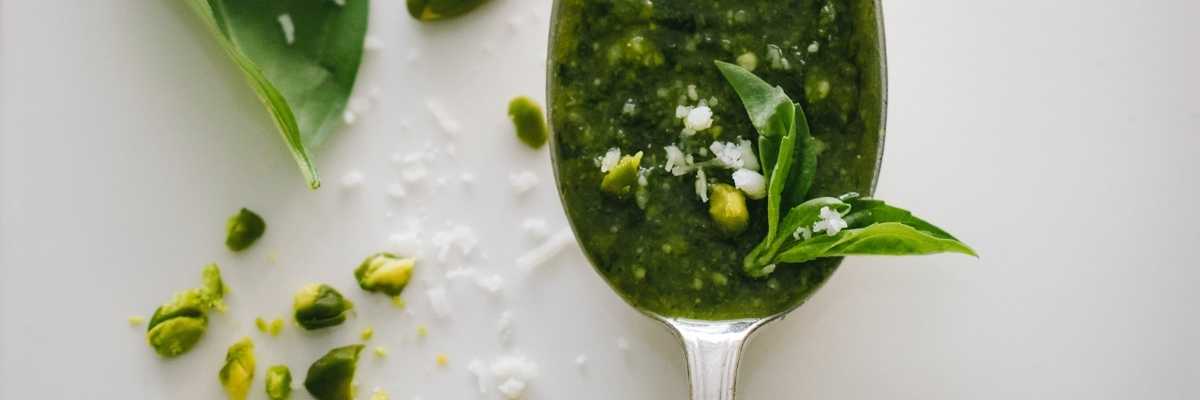 Pesto on a spoon with basil leaves around