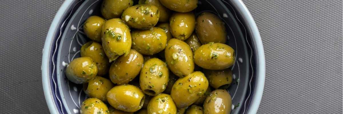 close up of green pickled olives in a bowl