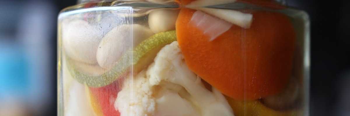 close up of pickled mixed vegetables in a lidded jar