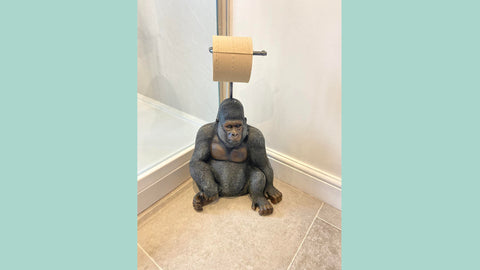 A freestanding toilet roll holder in the shape of a gorilla