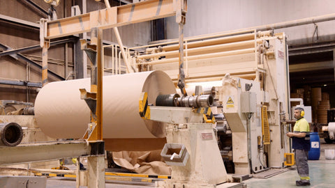 A huge parent roll of toilet paper being lifted by a machine