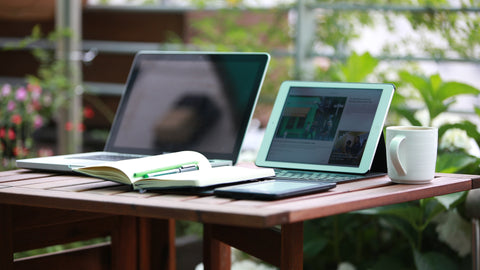 A computer and tablet sitting on a table outside