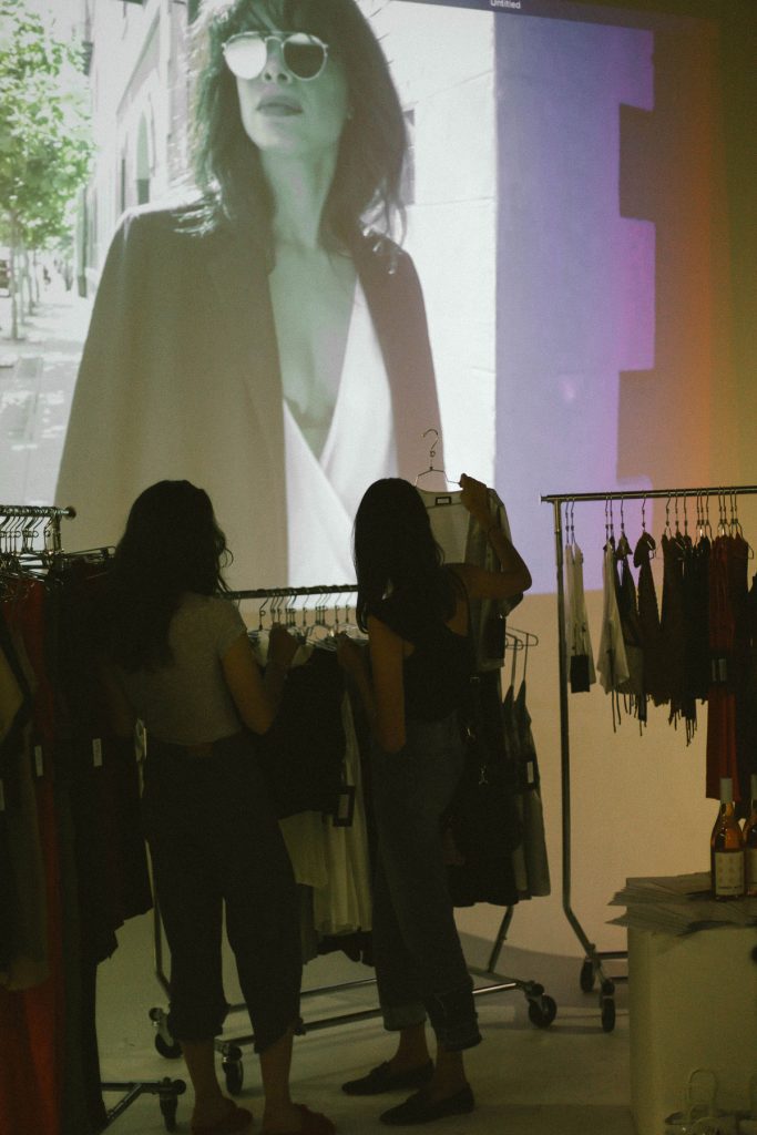 Silhouette of two customers looking at STL merchandise with a projected video of a model wearing the STL brand on the wall.