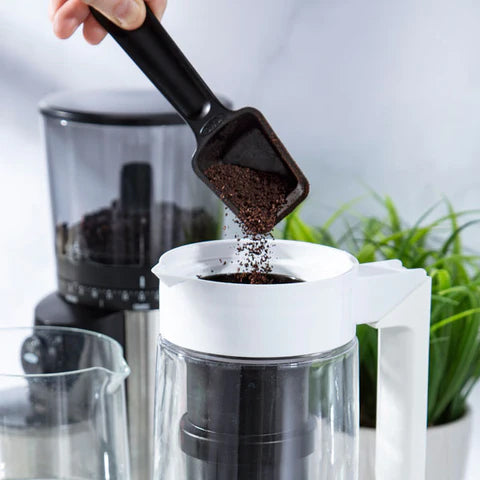 Pouring grinds into a cold brew coffee pitcher.