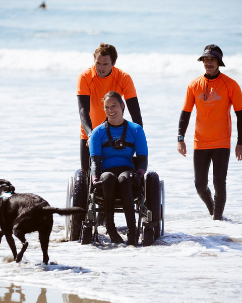 Adaptive surfer heading back in from water with Team Quinn