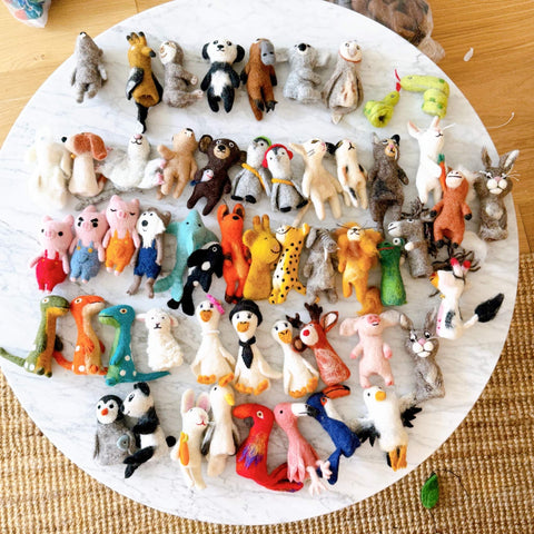 53 felt finger puppets created by Ganapati Crafts Co. laying out on a white table