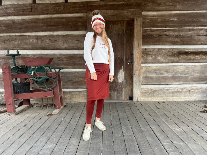 smiling young woman in winter hat, long sleeved shirt and red ankle length snoga