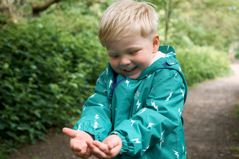 boy wearing muddy puddles scampsuit