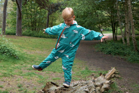 boy walking along log wearing puddlesuit