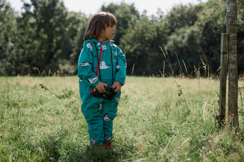 girl holding binoculars wearing avocet puddlesuit