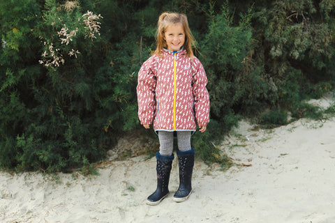 girl at beach wearing muddy puddles waterproofs