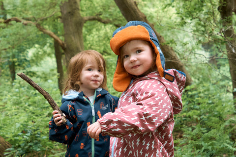children playing in woods wearing waterproofs
