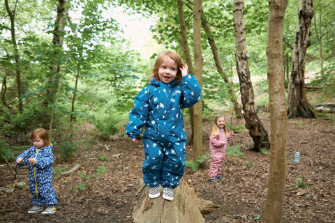 children playing in woods wearing muddy puddles waterproofs