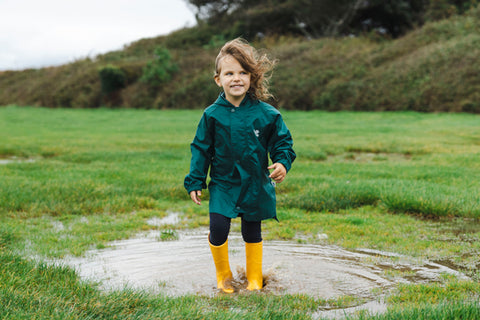 Girl jumping in muddy puddle wearing waterproofs