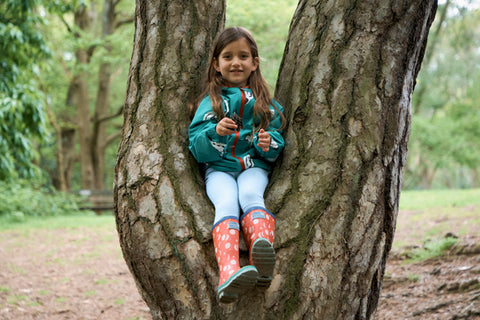 girl sitting in tree wearing waterproof jacket