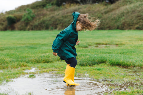 girl jumping in muddy puddle